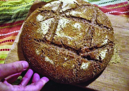 a hand turning a freshly baked loaf of bread